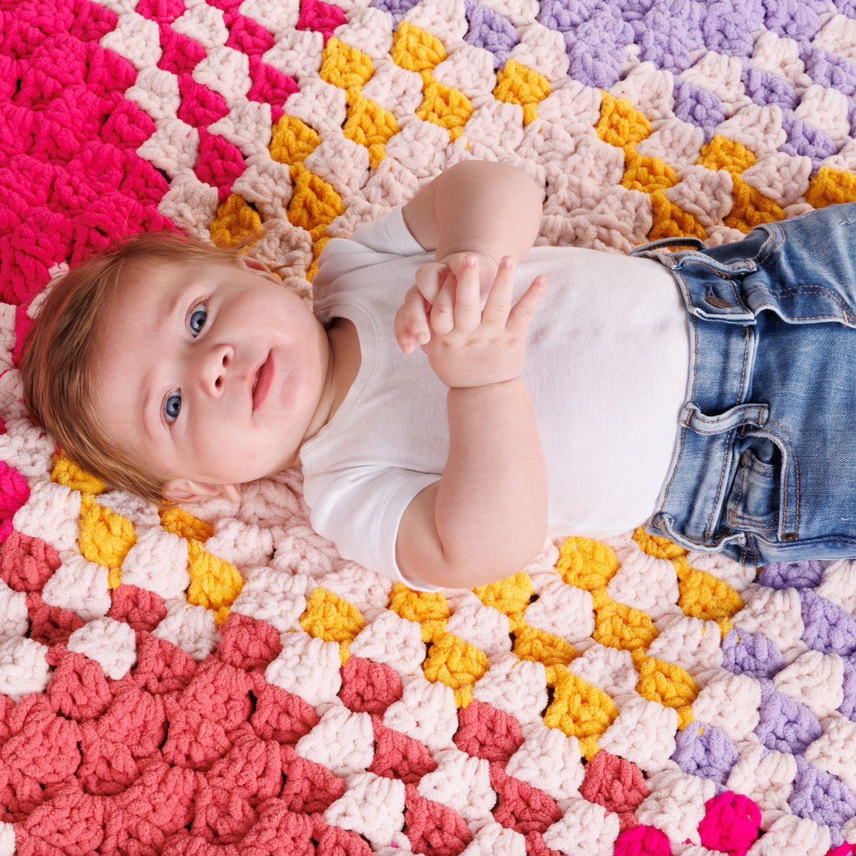 With All My Heart Crochet Blanket made using Bernat yarn in a styled lifestyle setting