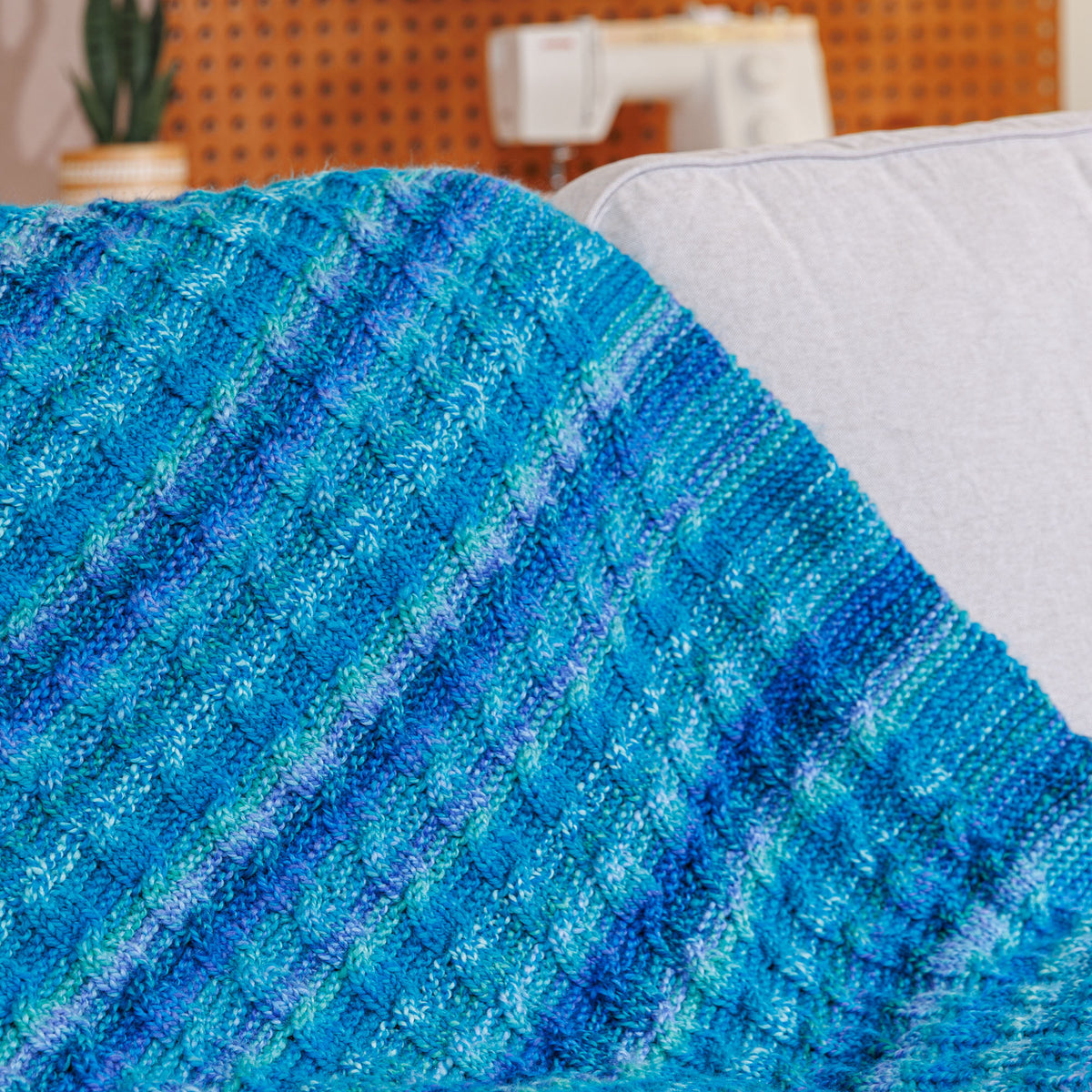 Knit Classic Cables Throw made using Bernat yarn in a styled lifestyle setting