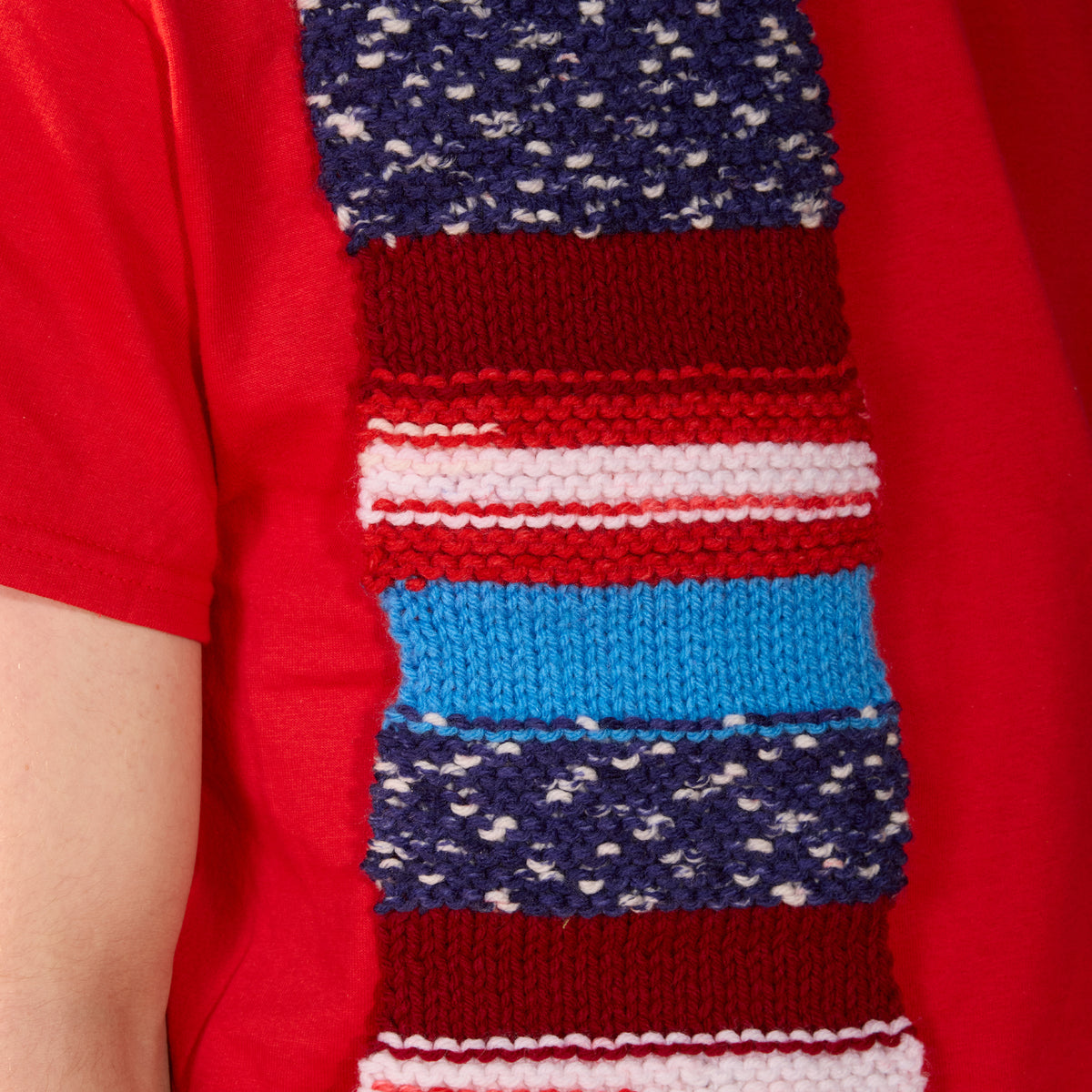 Americana Knit Scarf made using Red Heart yarn in a styled lifestyle setting
