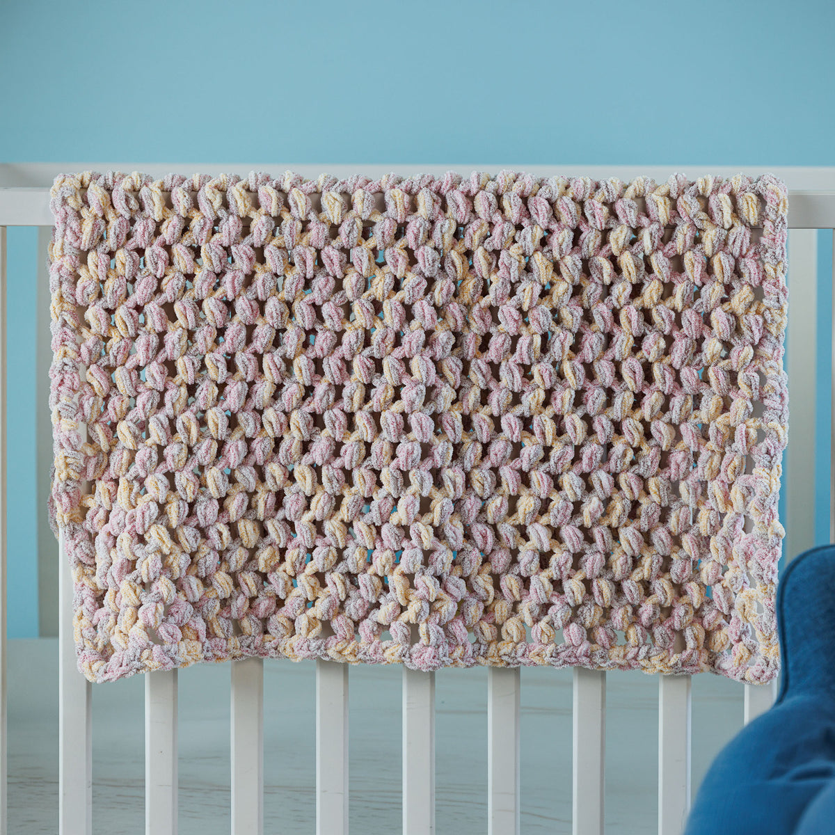 Puffs A Plenty Crochet Baby Blanket made using Bernat yarn in a styled lifestyle setting