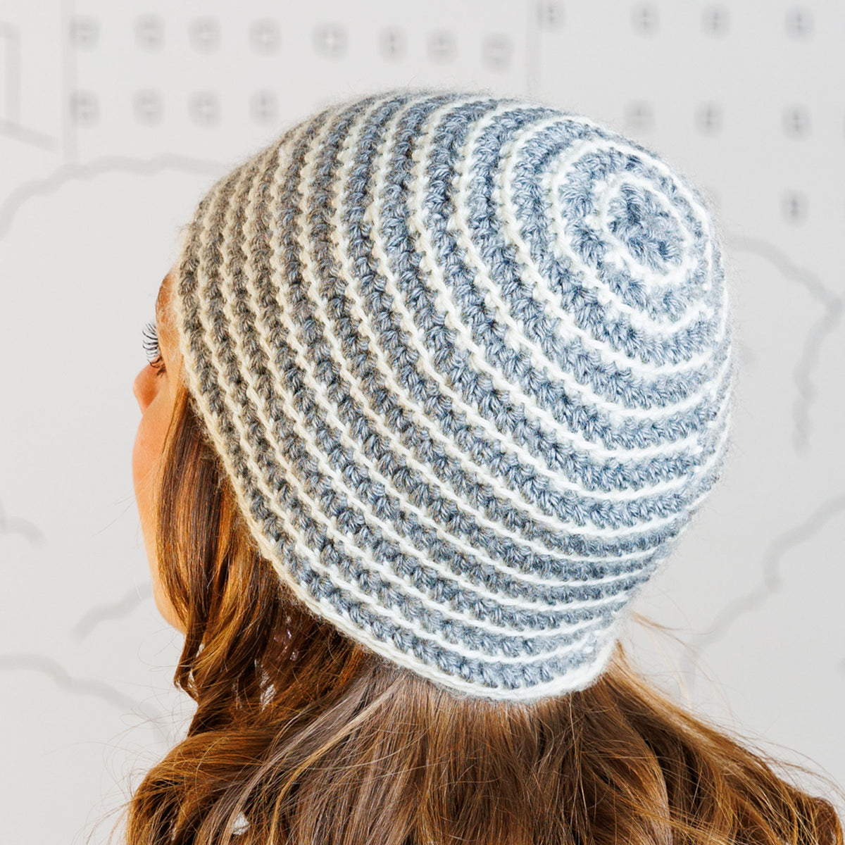 Person wearing a striped crochet beanie with a neutral background
