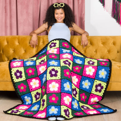Red Heart Crochet Flower Bed Blanket A crocheted blanket with a colorful floral pattern made using Red Heart All in One Flower Power yarn, Version 1